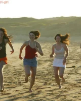Four girls come to the beach, take off the cloth to stay in bikinis and have fun nude in the water