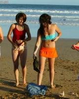 Four girls come to the beach, take off the cloth to stay in bikinis and have fun nude in the water