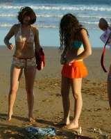 Four girls come to the beach, take off the cloth to stay in bikinis and have fun nude in the water