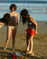 Four girls come to the beach, take off the cloth to stay in bikinis and have fun nude in the water