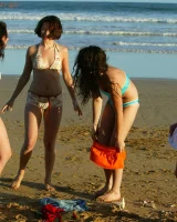 Four girls come to the beach, take off the cloth to stay in bikinis and have fun nude in the water