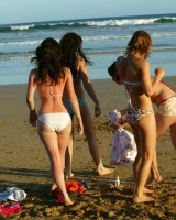 Four girls come to the beach, take off the cloth to stay in bikinis and have fun nude in the water