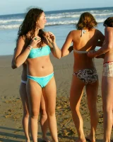 Four girls come to the beach, take off the cloth to stay in bikinis and have fun nude in the water