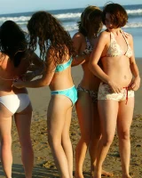 Four girls come to the beach, take off the cloth to stay in bikinis and have fun nude in the water