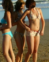 Four girls come to the beach, take off the cloth to stay in bikinis and have fun nude in the water