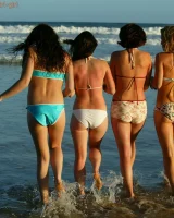Four girls come to the beach, take off the cloth to stay in bikinis and have fun nude in the water