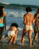 Four girls come to the beach, take off the cloth to stay in bikinis and have fun nude in the water