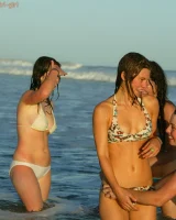 Four girls come to the beach, take off the cloth to stay in bikinis and have fun nude in the water