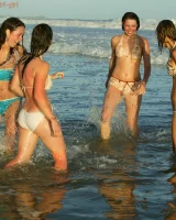 Four girls come to the beach, take off the cloth to stay in bikinis and have fun nude in the water