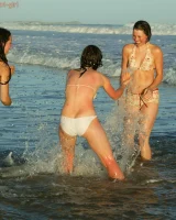 Four girls come to the beach, take off the cloth to stay in bikinis and have fun nude in the water