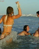 Four girls come to the beach, take off the cloth to stay in bikinis and have fun nude in the water