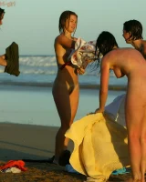 Four girls come to the beach, take off the cloth to stay in bikinis and have fun nude in the water