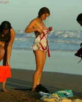 Four girls come to the beach, take off the cloth to stay in bikinis and have fun nude in the water