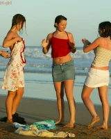 Four girls come to the beach, take off the cloth to stay in bikinis and have fun nude in the water