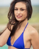 Pretty girl Edessa G removes her bikini to pose naked on a poolside chair