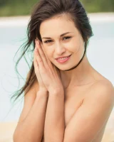 Pretty girl Edessa G removes her bikini to pose naked on a poolside chair