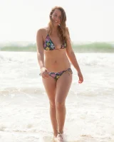 Busty skateboard chick Dharma Webb in tight shorts rides to the beach to swim in sexy bikini and to get a tan