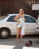 Busty skateboard chick Dharma Webb in tight shorts rides to the beach to swim in sexy bikini and to get a tan