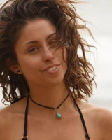 Brunette American Sonya Ash strips her bikini top on the beach and poses