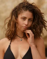 Brunette American Sonya Ash strips her bikini top on the beach and poses