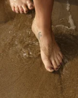 Brunette American Sonya Ash strips her bikini top on the beach and poses