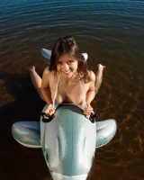 Playing on toy dolphin in sexy white bikini and nude in the lake