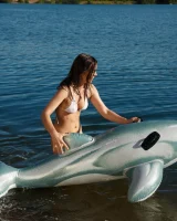 Playing on toy dolphin in sexy white bikini and nude in the lake