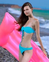 Young playful puffy nipples brunette baby in blue bikini goes nude on the beach on toy float