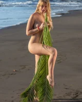 Blonde beach fairy in red bikini with green palm leaf strips her puffy nipples sexy body