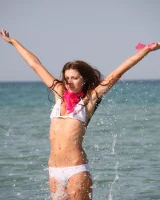 Slim body sexy brunette in white bikini is naked in the sea