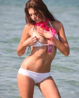 Slim body sexy brunette in white bikini is naked in the sea