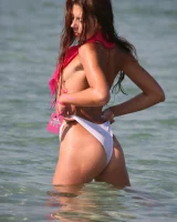 Slim body sexy brunette in white bikini is naked in the sea