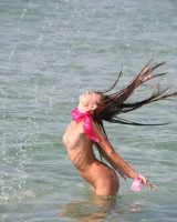 Slim body sexy brunette in white bikini is naked in the sea