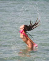 Slim body sexy brunette in white bikini is naked in the sea