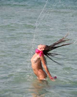 Slim body sexy brunette in white bikini is naked in the sea