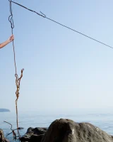 Slim body girl in pink bikini is nude at the seaside on big stone