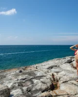 Exciting blonde in red micro bikini is nude on the sea rocks