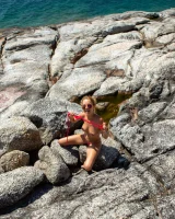 Exciting blonde in red micro bikini is nude on the sea rocks