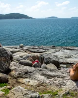 Exciting blonde in red micro bikini is nude on the sea rocks
