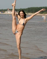 Exciting young flexible brunette in bikini outside in the water