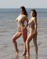 Two girlfriends in bikinis poses in the water outside
