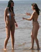 Two girlfriends in bikinis poses in the water outside