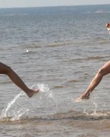 Two girlfriends in bikinis poses in the water outside