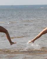 Two girlfriends in bikinis poses in the water outside