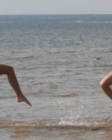 Two girlfriends in bikinis poses in the water outside