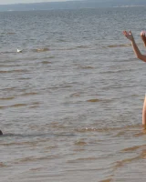 Two girlfriends in bikinis poses in the water outside