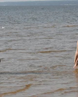 Two girlfriends in bikinis poses in the water outside