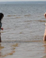 Two girlfriends in bikinis poses in the water outside