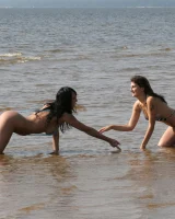 Two girlfriends in bikinis poses in the water outside