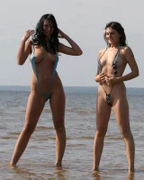 Two girlfriends in bikinis poses in the water outside
